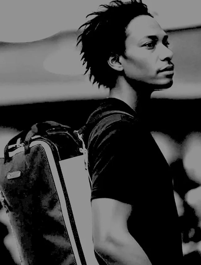 Schwarz weiß Banner für 7Clouds. Ein junger Mann mit kurzen Dreadlocks trägt einen nachhaltigen Rucksack von 7Clouds auf der Schulter. Der Rucksack besteht aus recycelten Materialien in einem kontrastreichen Design mit heller Vorderseite und dunklen Seitenteilen. Das Bild betont urbane Coolness, Nachhaltigkeit und die klare Formsprache der Marke.