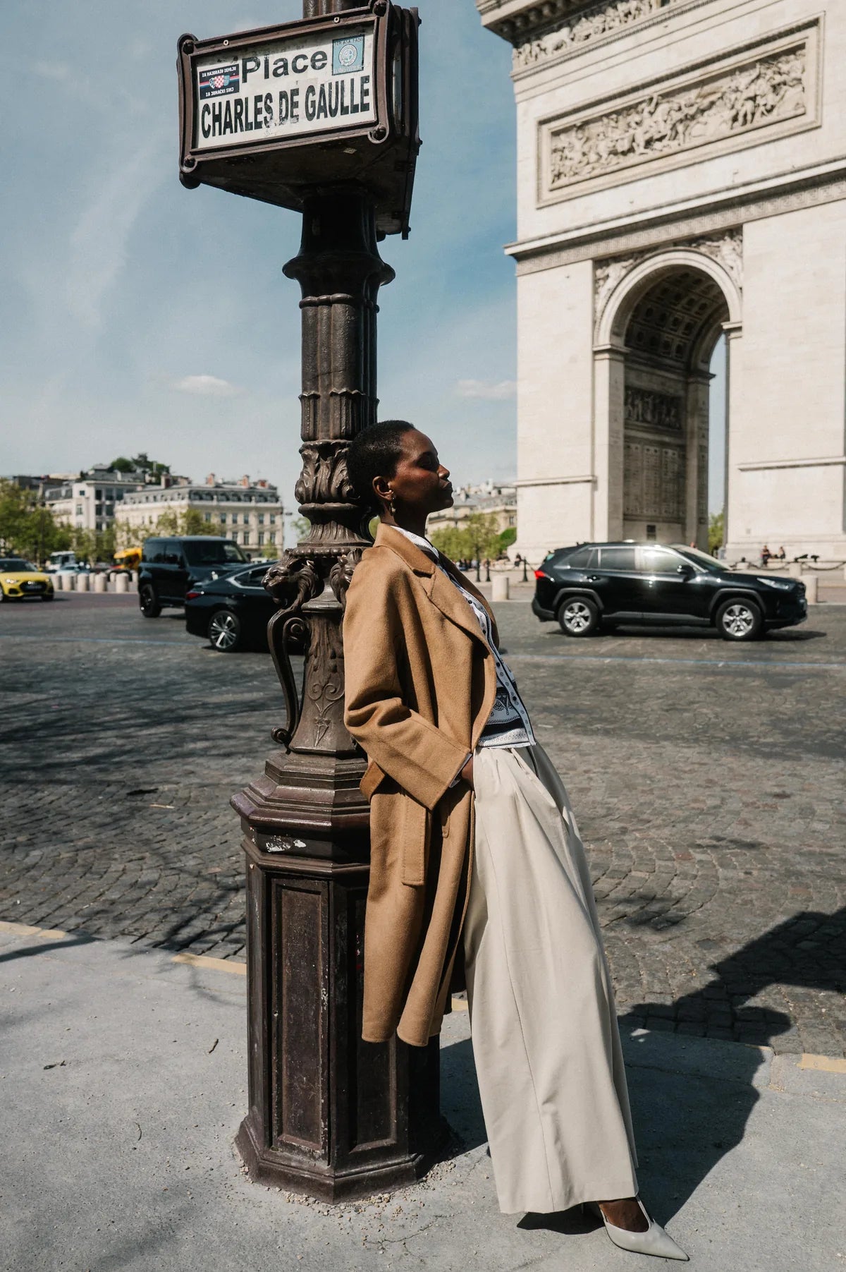 Model in camelfarbenem Wollmantel an einer Laterne beim Arc de Triomphe – Herzens Herbst/Winter 2026