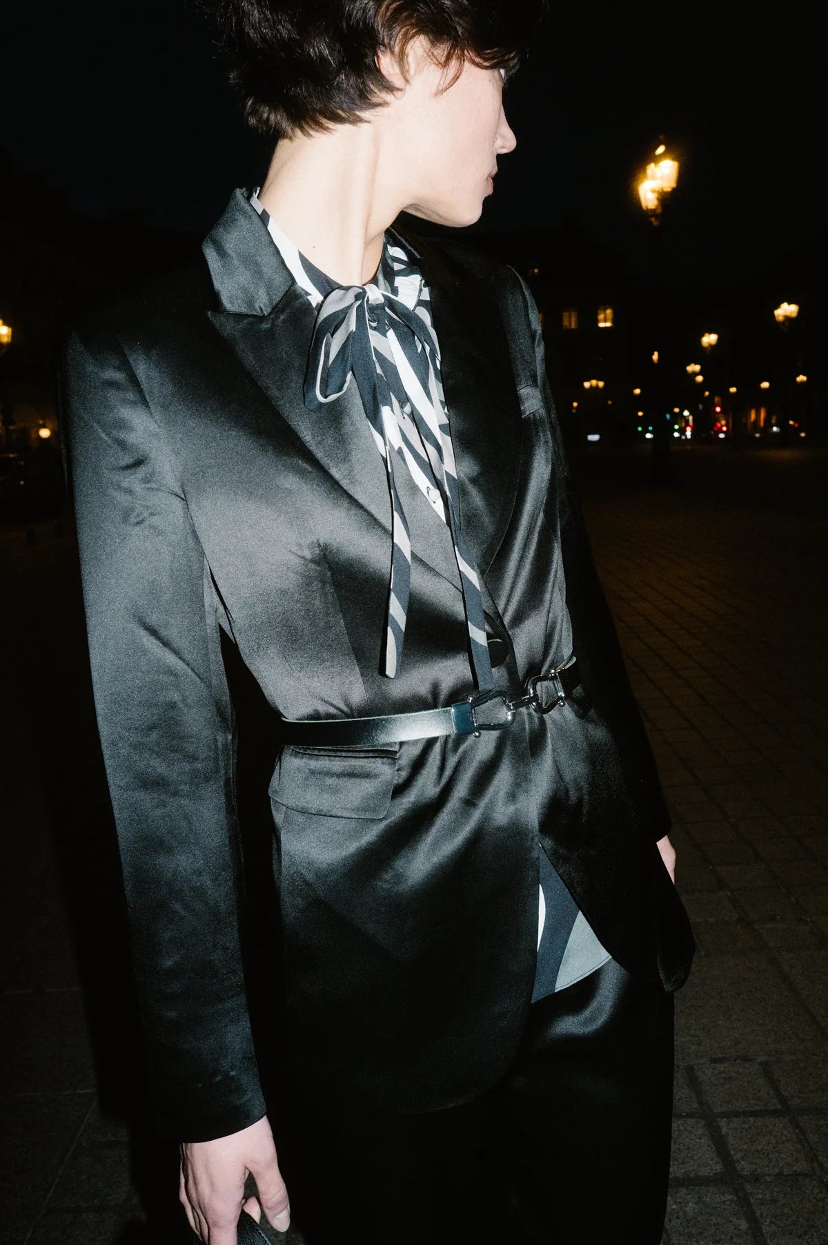 Model in schwarzem Satin-Blazer mit Schluppenbluse bei Nacht in Paris – Herzens Herbst/Winter 2026