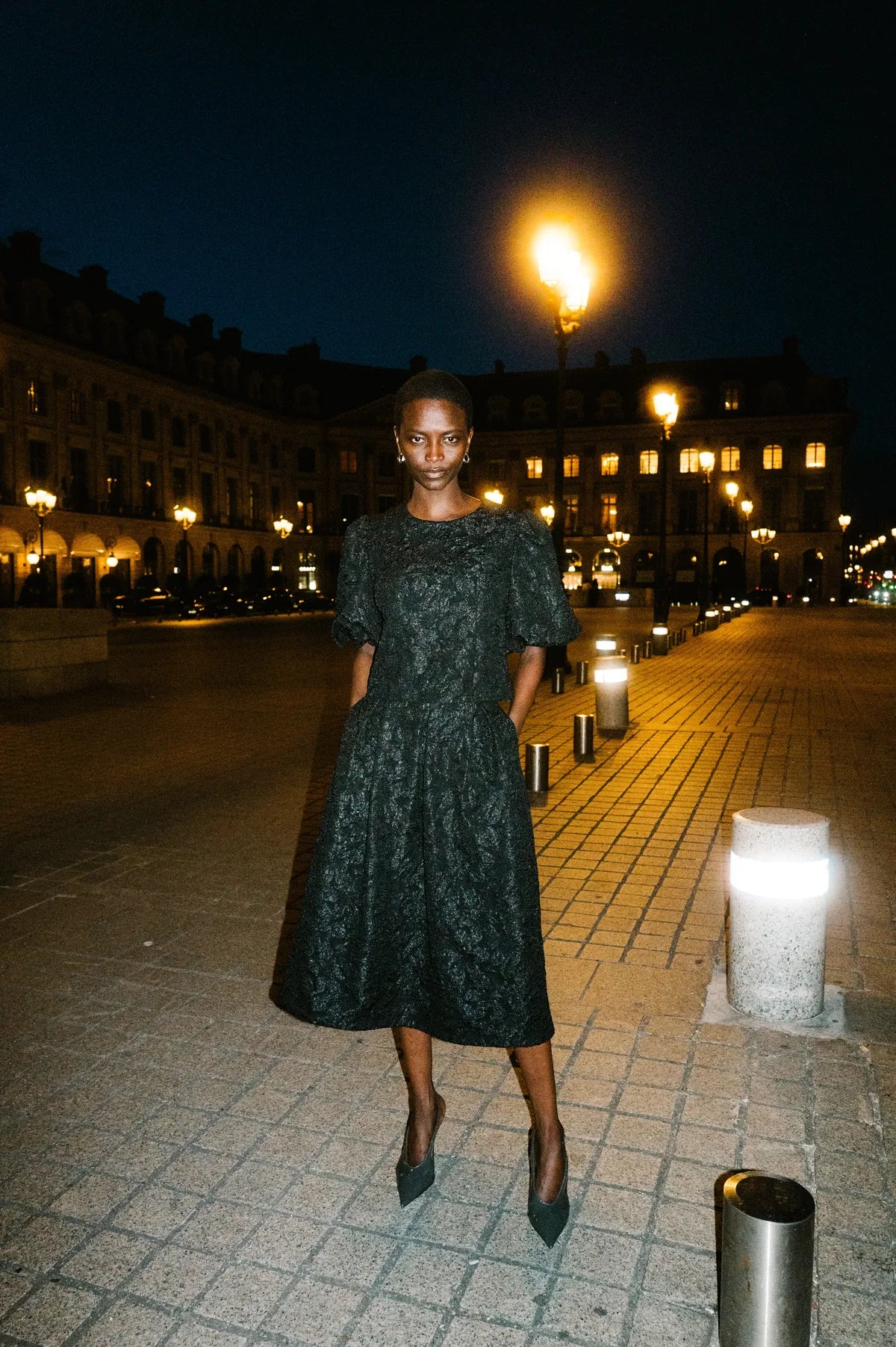 Model im schwarzen Brokat-Look auf der nächtlichen Place Vendôme – Herzens Herbst/Winter 2026