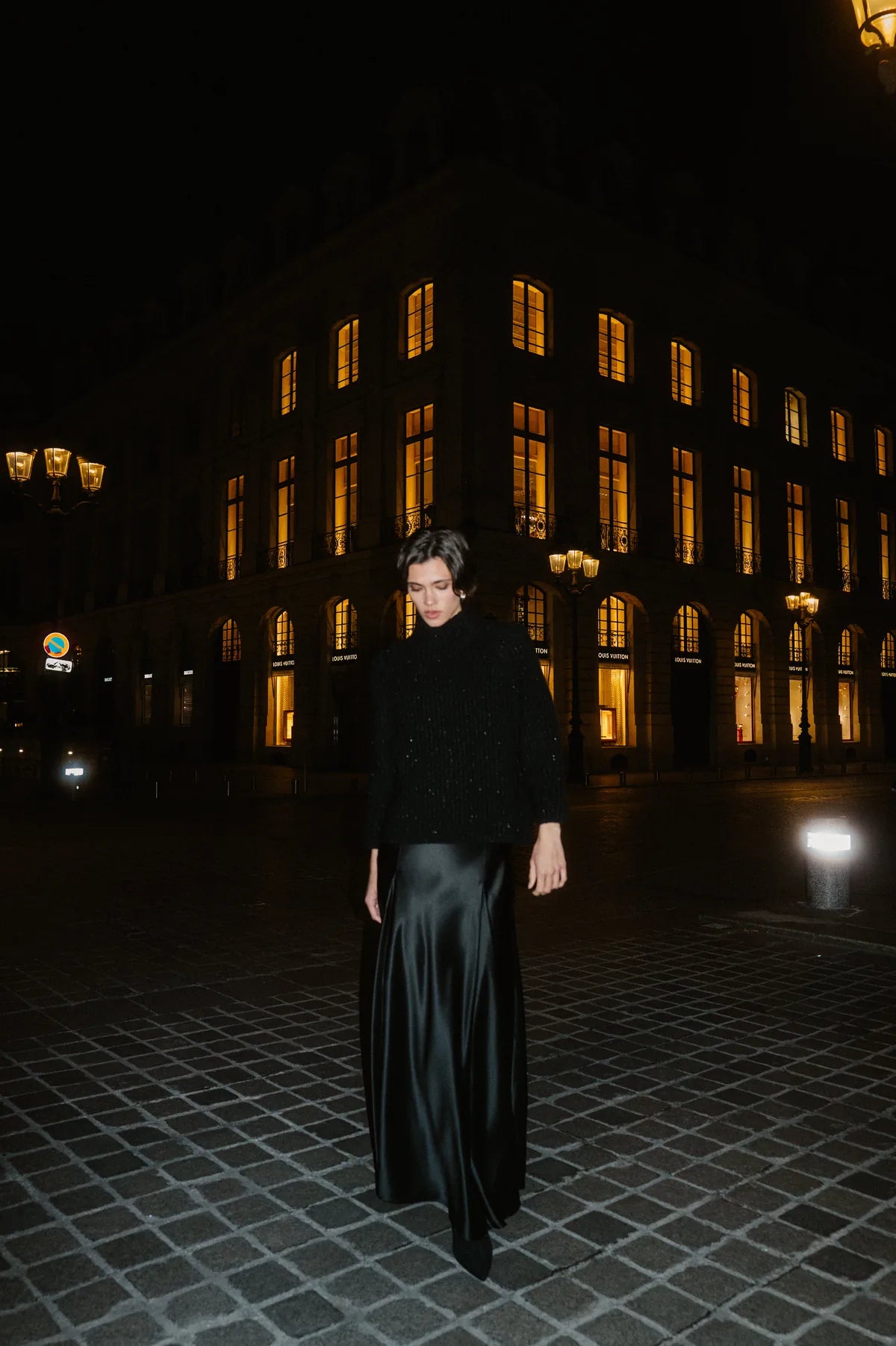 Model in schwarzem Pullover und Satinrock bei Nacht in Paris – Herzens Herbst/Winter 2026