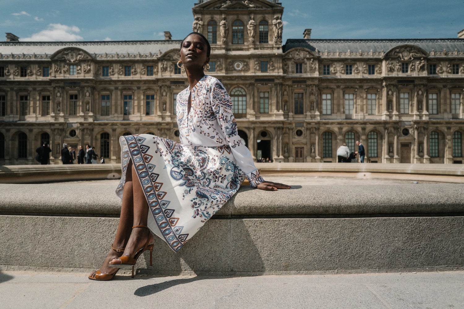 Model im Paisley-Seidenkleid sitzend vor dem Louvre – Herzens Herbst/Winter 2026
