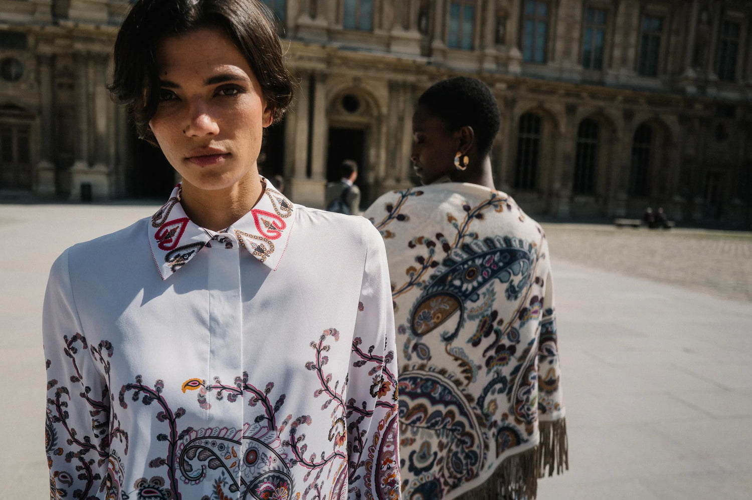 Model in Seidenbluse mit Paisley-Kragen und Model mit Fransentuch im Louvre-Hof – Herzens Herbst/Winter 2026