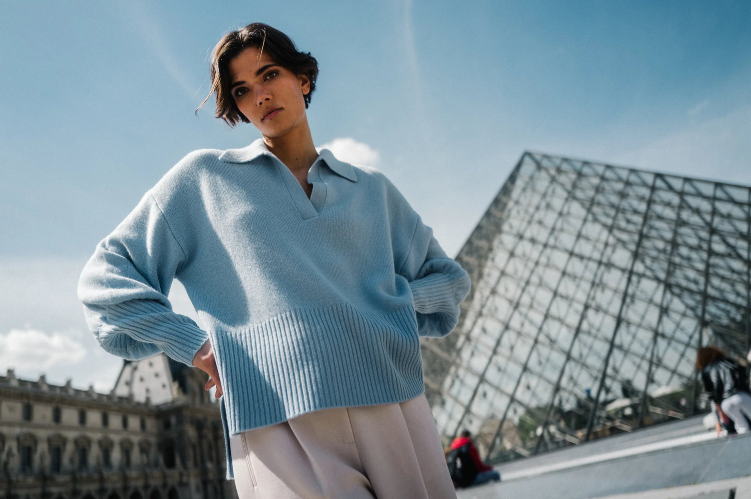 Model in hellblauem Strickpullover vor der Louvre-Pyramide – Herzens Herbst/Winter 2026