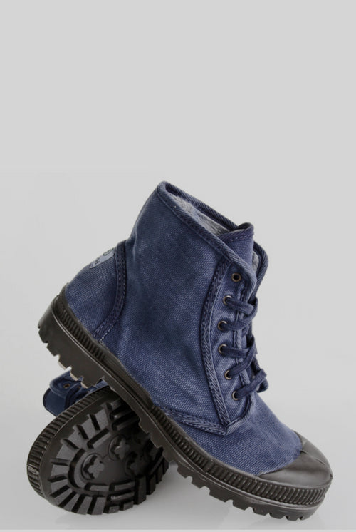 Nachhaltige Natural World Schuhe in Dunkelblau aus Canvas mit schwarzer Gummikappe und robuster, profilierter Sohle. Das Paar ist modern inszeniert – ein Schuh steht aufrecht, während der andere seitlich lehnt und die strapazierfähige Sohle zeigt. Hergestellt aus umweltfreundlichen Materialien und mit vulkanisierter Sohle, repräsentieren die Schuhe den ökologischen Anspruch der Marke.