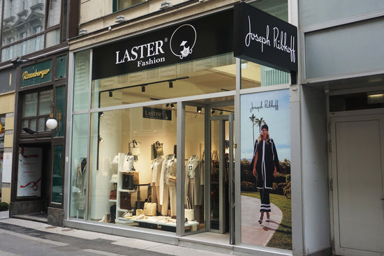 Eingang der Laster Fashion Filiale in Wien mit Joseph Ribkoff Logo. Außenansicht des Stores mit moderner Schaufenstergestaltung.